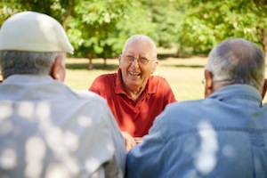 Active retired senior people, old friends and leisure, group of three elderly men having fun, laughing and talking in city park. Waist up